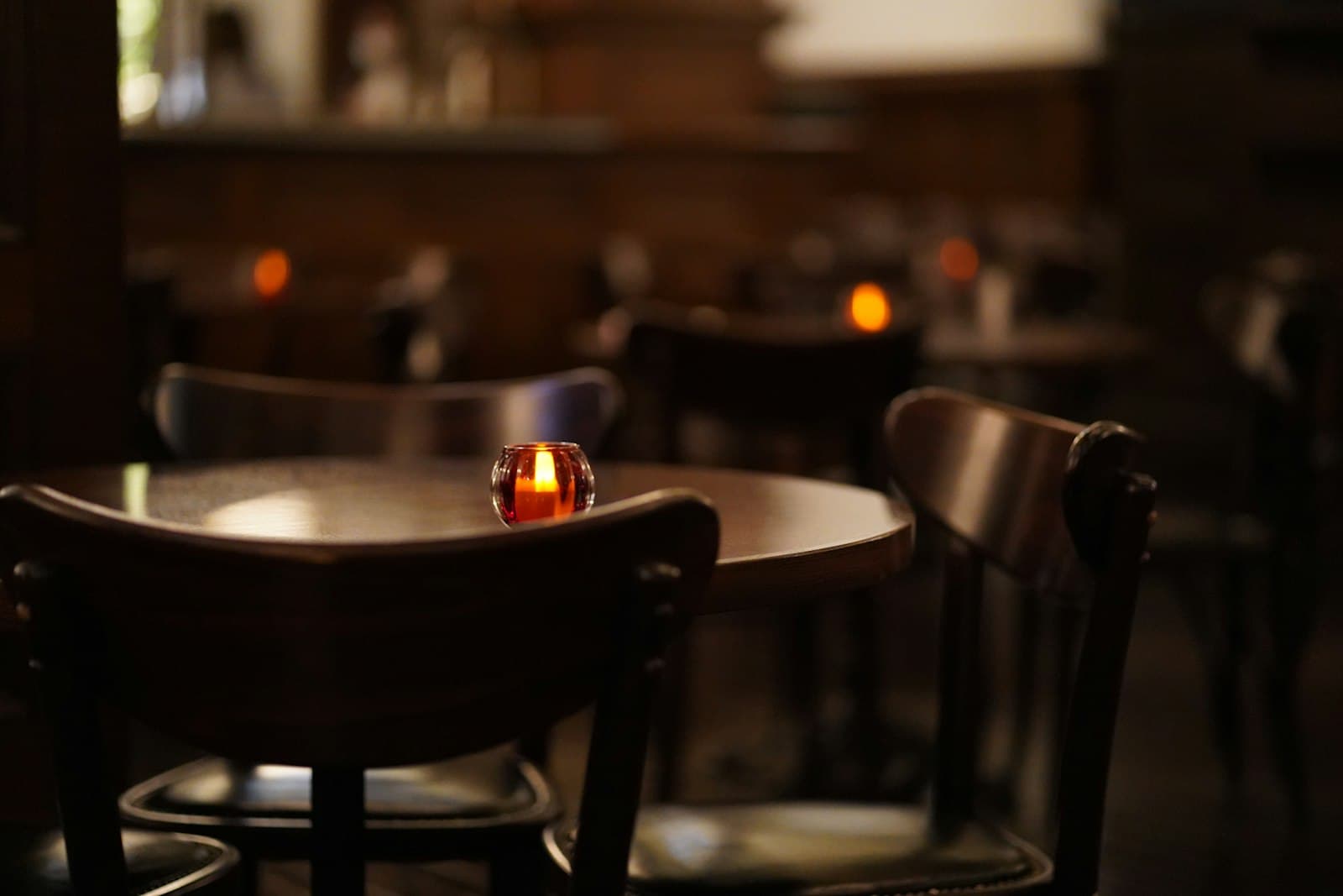 A single candle burning on a dark café table