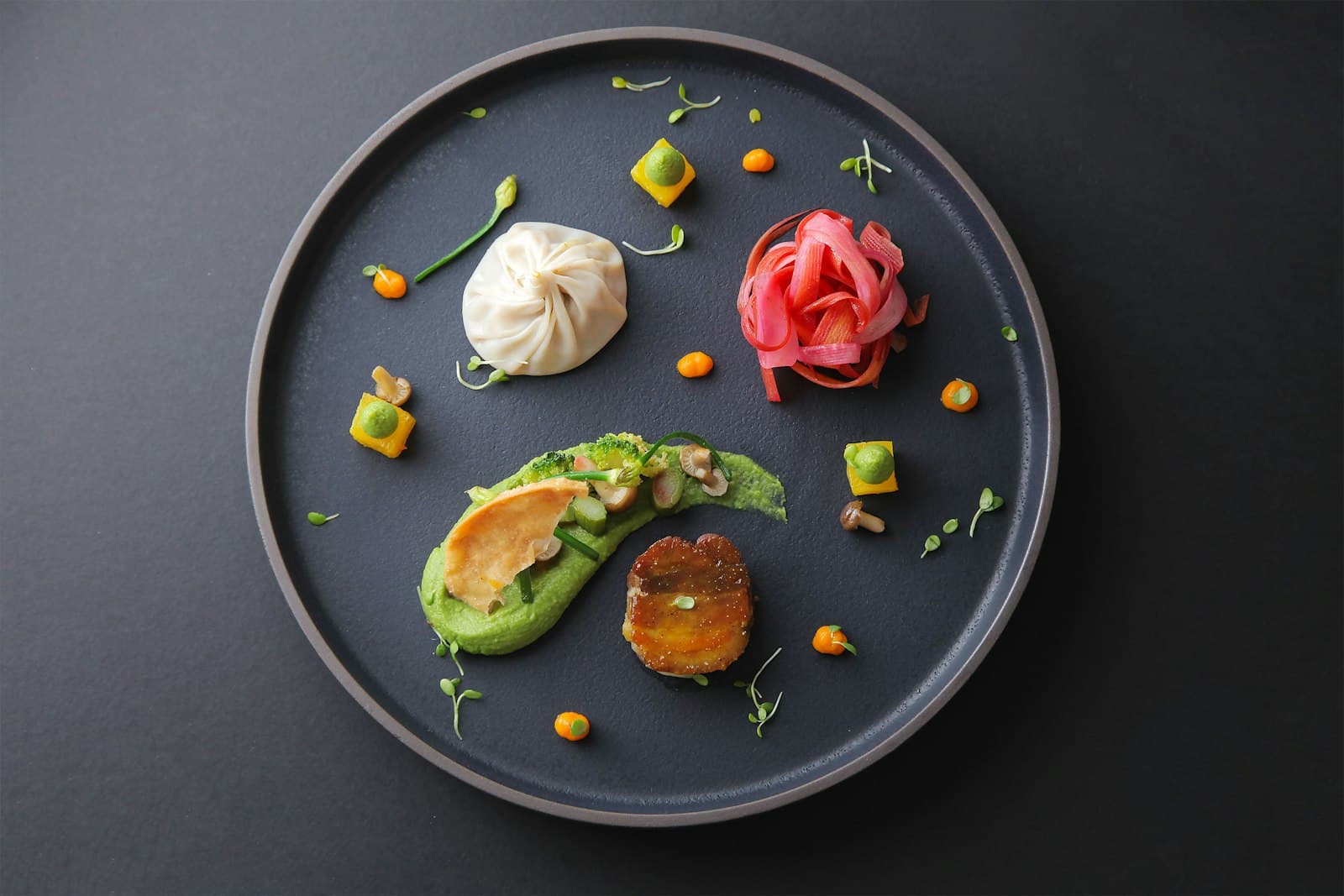 A dark slate plate composed with delicate garnishes