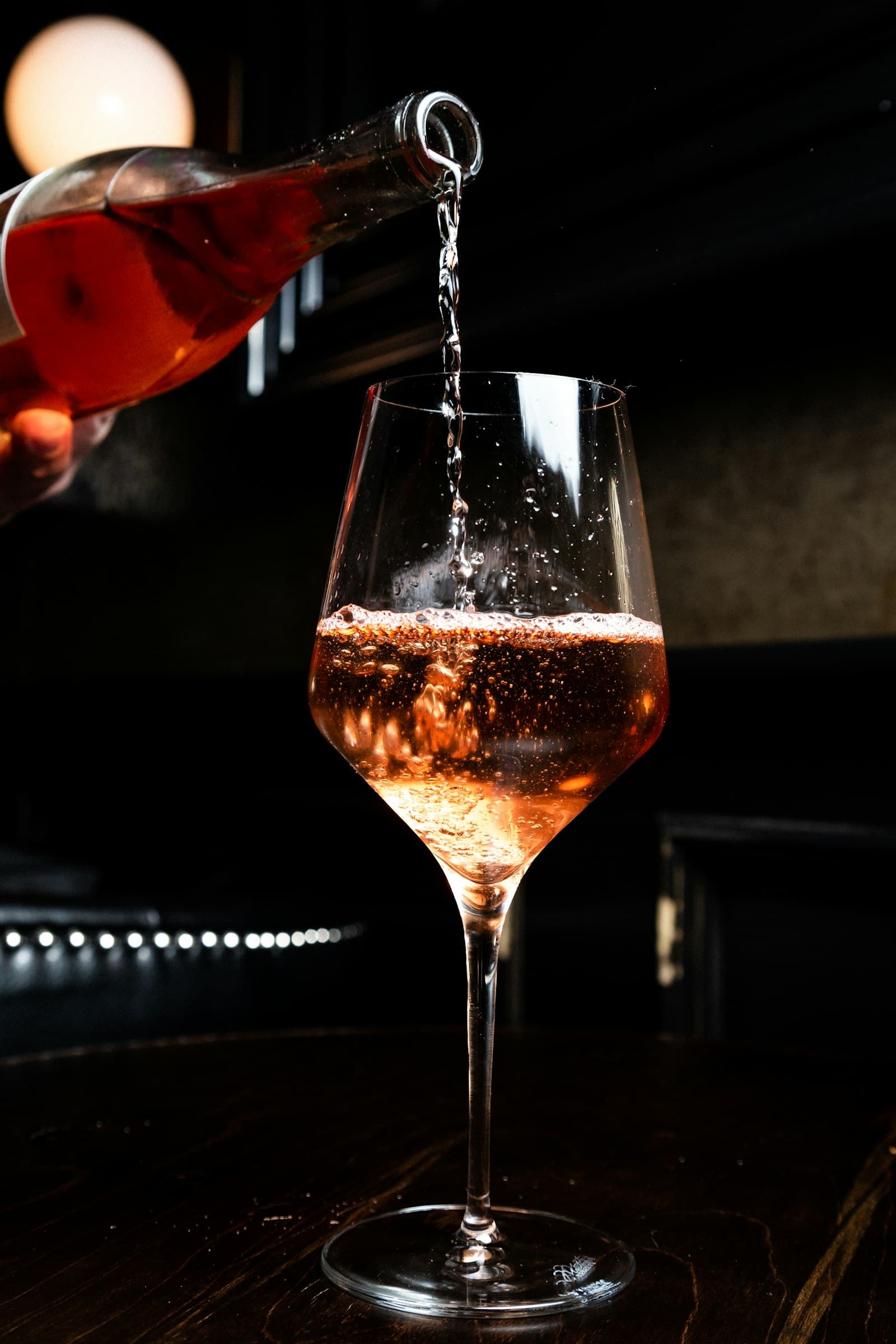 Wine poured into a glass against the dark of the bar